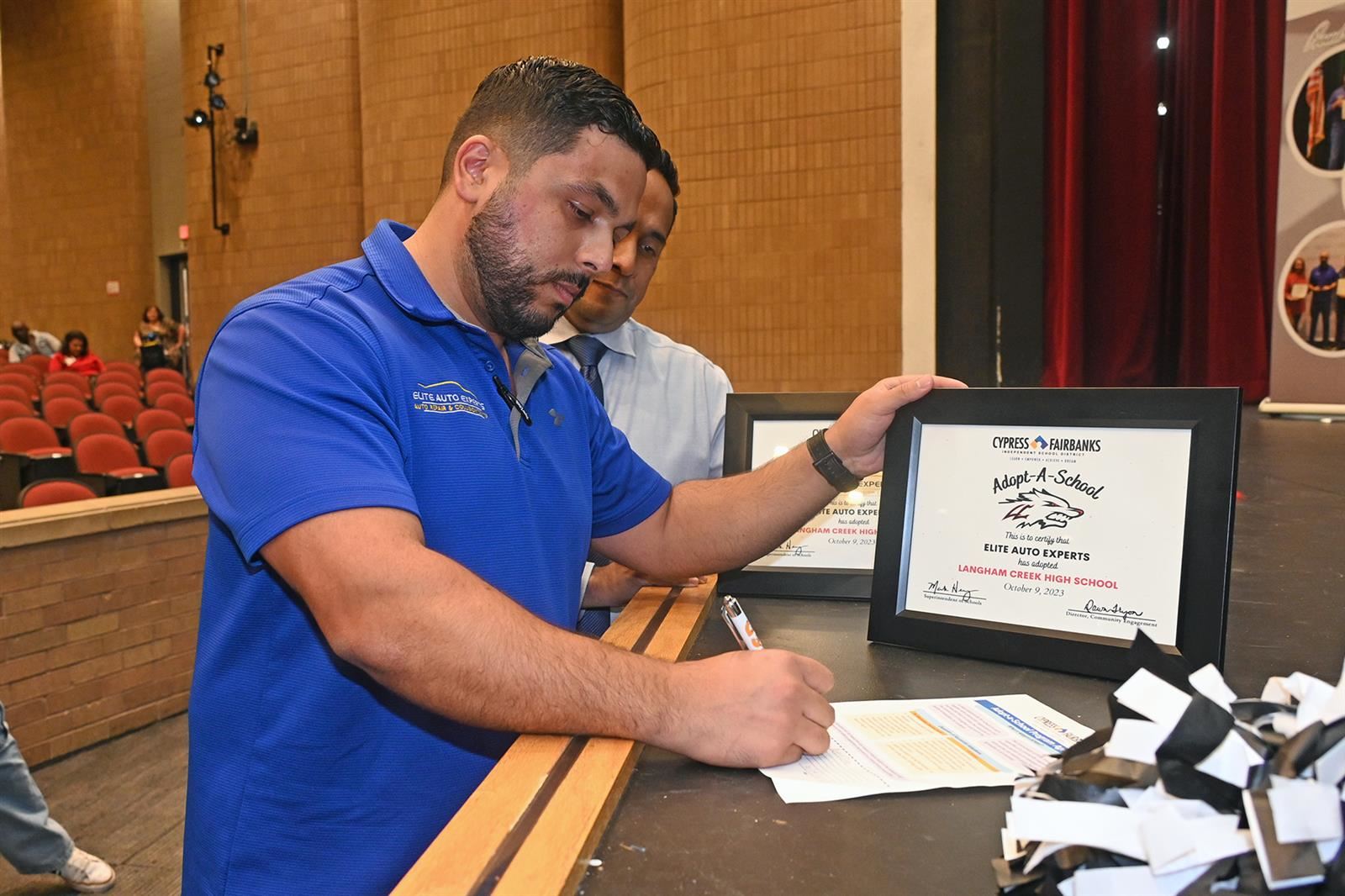 Moe Rabieh, Elite Auto Experts owner, signs an Adopt-a-School partnership agreement.